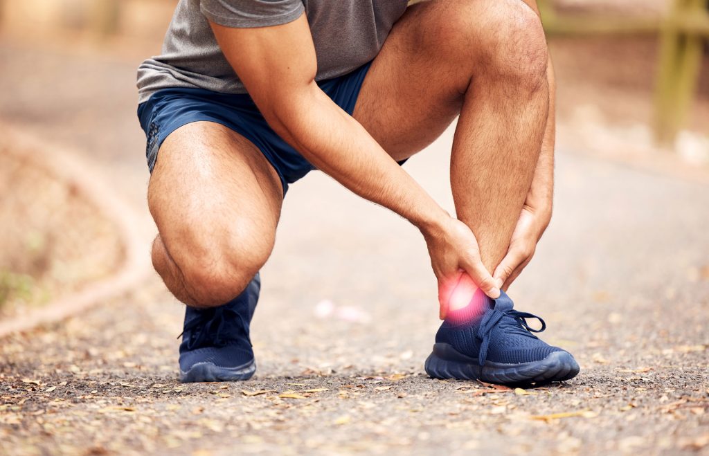 A shot of man holding his foot due to achilles tendon injuries.