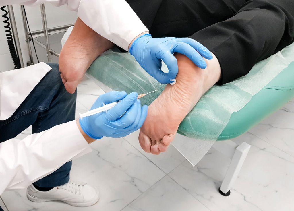 Doctor doing injection to patients foot.