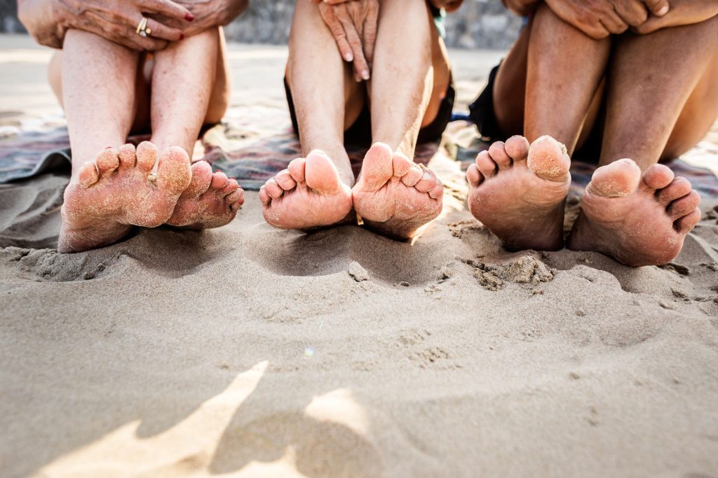 Friends barefoot on beach enjoying the sand.