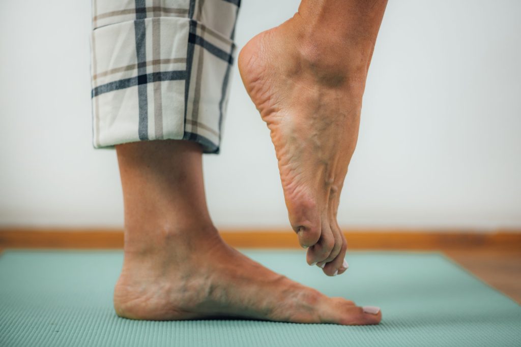 Person balancing with 1 feet in a yoga mat.